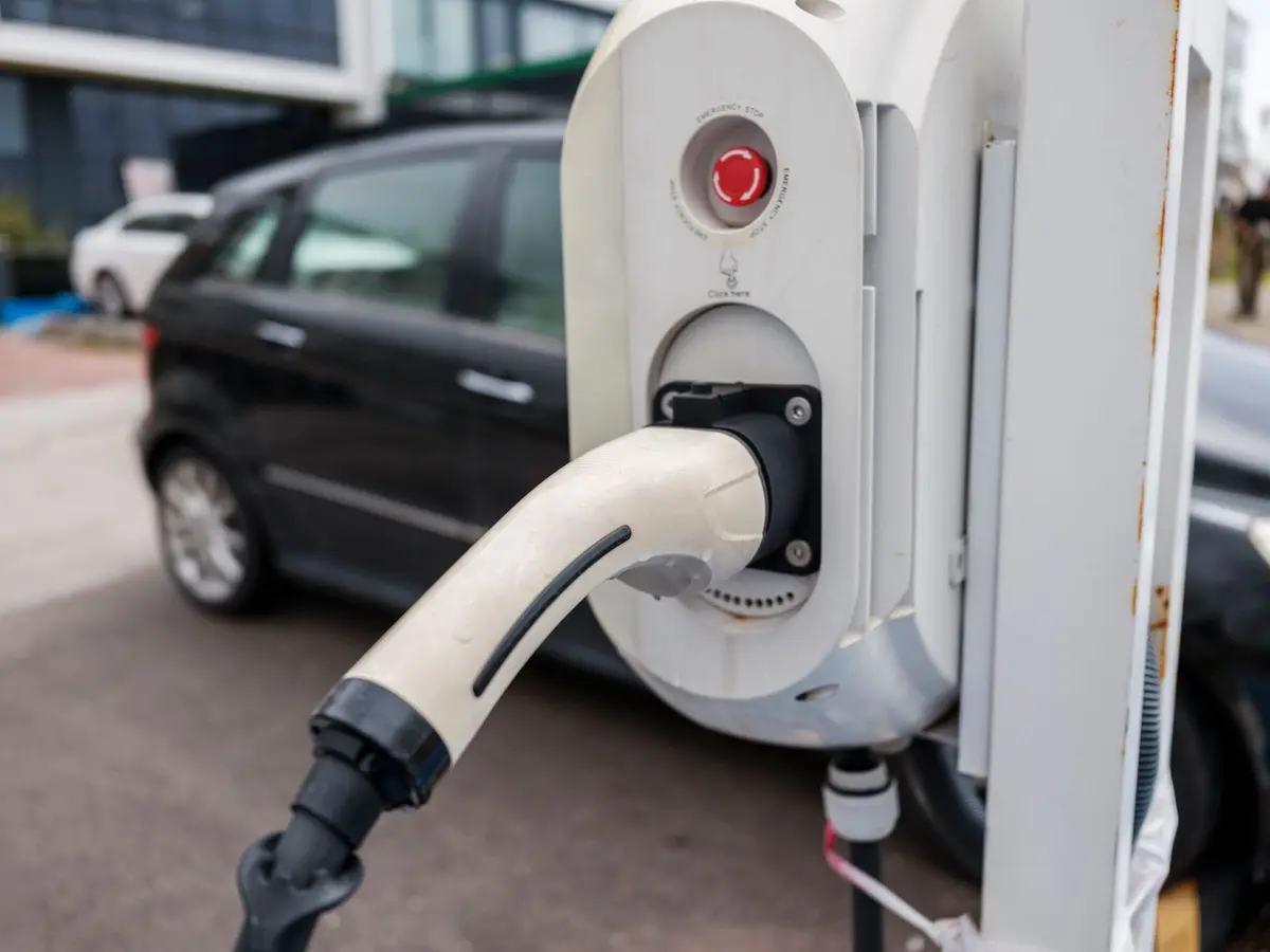 Pistolet de recharge branché sur une borne, voiture garée à côté