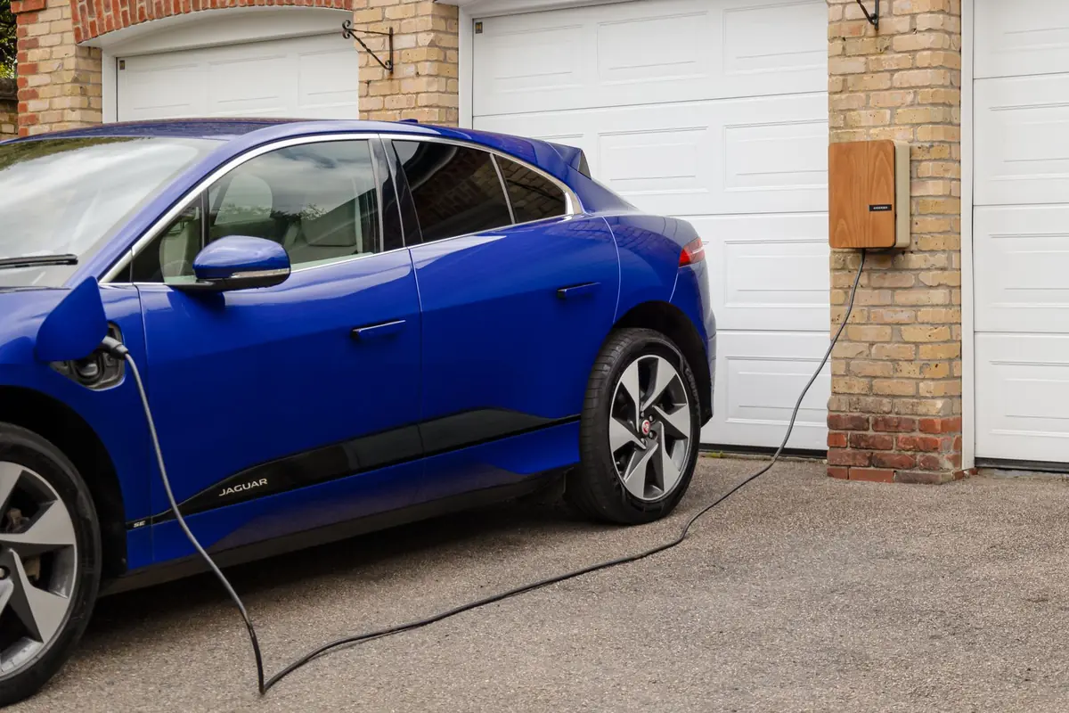 Voiture électrique en charge sur une borne murale installée devant un garage