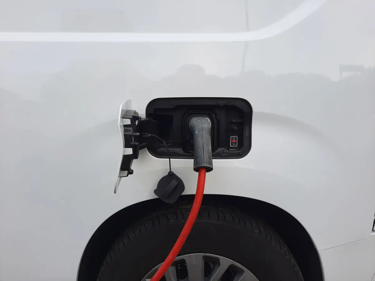 Câble de recharge rouge branché sur la trappe d’une voiture électrique